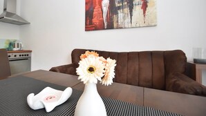 A living room with a brown sofa, a white vase with flowers, and a painting on the wall. - Wohnung in Willingen Nahe Ettelsberg-bahn (Willingen)