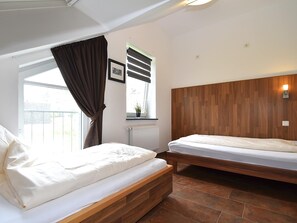 A bedroom with two beds, a window with curtains, a radiator, and a wall-mounted light fixture. - Wohnung in Willingen Nahe Ettelsberg-bahn (Willingen)