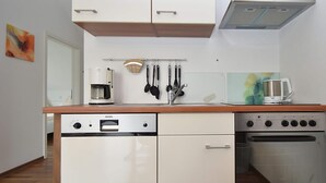 A compact kitchen with white cabinetry, a coffee maker, a kettle, and a stove. - Wohnung in Willingen Nahe Ettelsberg-bahn (Willingen)