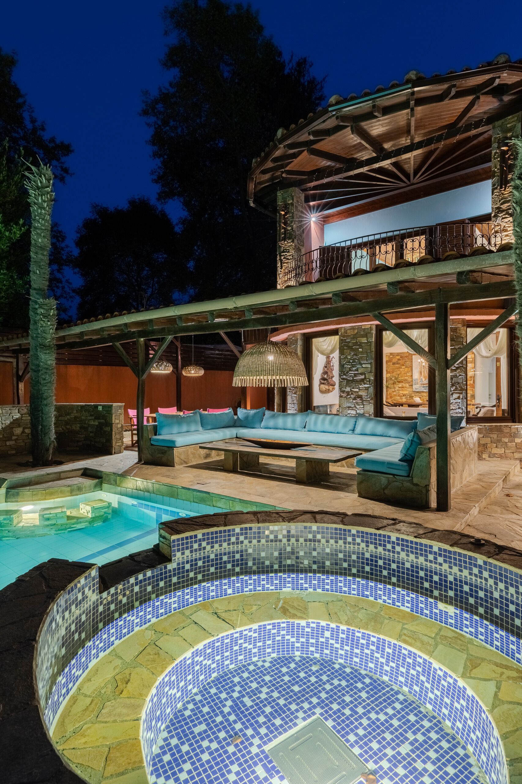 Et poolområde med et mosaik-spa, en træterrasse og et overdækket opholdsområde med hynder.
