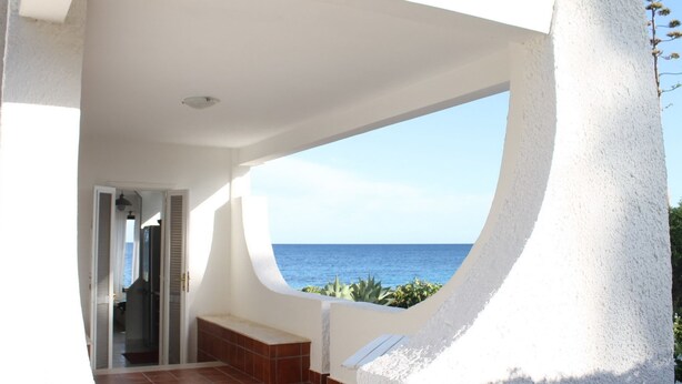A modern building with a curved balcony overlooking the sea. - Belvilla by OYO Villa Eirene (Syracuse)