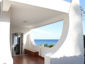 A modern building with a curved balcony overlooking the sea.