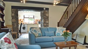 Una sala de estar con un sofá azul, una mesa de centro de madera y una escalera.