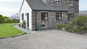Una casa de piedra de dos pisos con fachada blanca y techo inclinado.