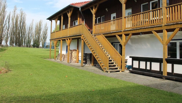 A wooden building with a balcony and a staircase leading to the upper floor. - Spacious Apartment in Boddin With Garden (Walkendorf)