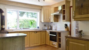 A kitchen with wooden cabinets, a built-in oven, and a window with a view of greenery.