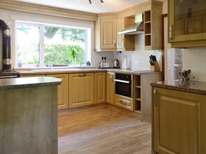 A kitchen with wooden cabinets, a built-in oven, and a window with a view of greenery.