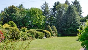 A well-maintained garden with neatly trimmed hedges and a variety of trees.