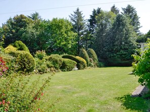A well-maintained garden with neatly trimmed hedges and a variety of trees.
