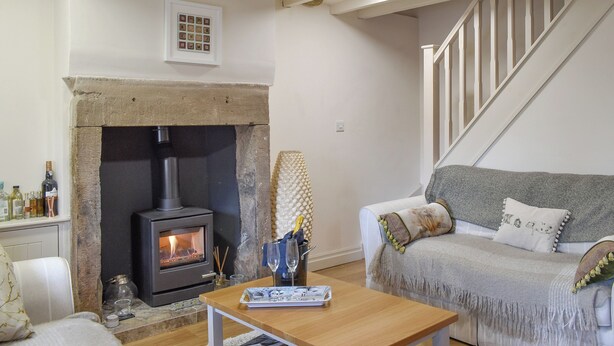 A cozy living room with a stone fireplace, a sofa, and a wooden coffee table. - 2 bedroom accommodation in Bamford, near Hope Valley (Bamford, near Hope Valley)