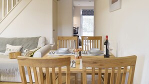 A dining area with a wooden table set for four, surrounded by wooden chairs. A staircase is visible in the background, leading to an upper level. - 2 bedroom accommodation in Bamford, near Hope Valley (Bamford, near Hope Valley)