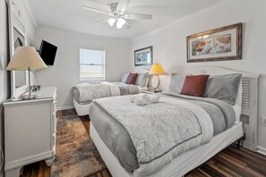Two single beds, a ceiling fan, and a bedside table with a lamp are featured in this well-appointed bedroom.