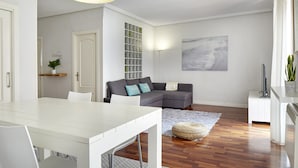 A modern living room with a white dining table, grey sofa, and a large abstract painting on the wall. - Always Easy I Escolta Real (San Sebastián/Donostia)
