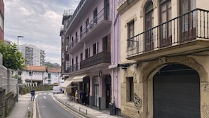 A street with buildings, including a two-story building with balconies and a garage door with graffiti. - Always Easy I Escolta Real (San Sebastián/Donostia)