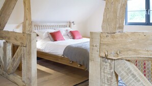 A rustic wooden bed with a white headboard, pink pillows, and a grey knitted blanket. - The Garden Room at Eudon George (Eudon George, near Bridgnorth)