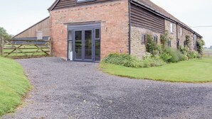 A brick building with a large door and windows, surrounded by a gravel driveway and greenery. - The Garden Room at Eudon George (Eudon George, near Bridgnorth)