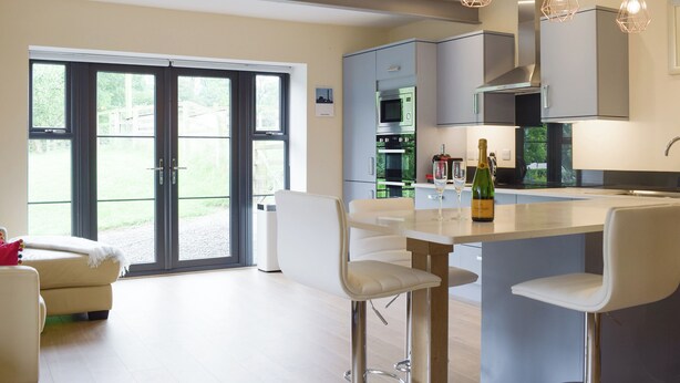 A modern kitchen with a central island, bar stools, and pendant lighting. - The Garden Room at Eudon George (Eudon George, near Bridgnorth)