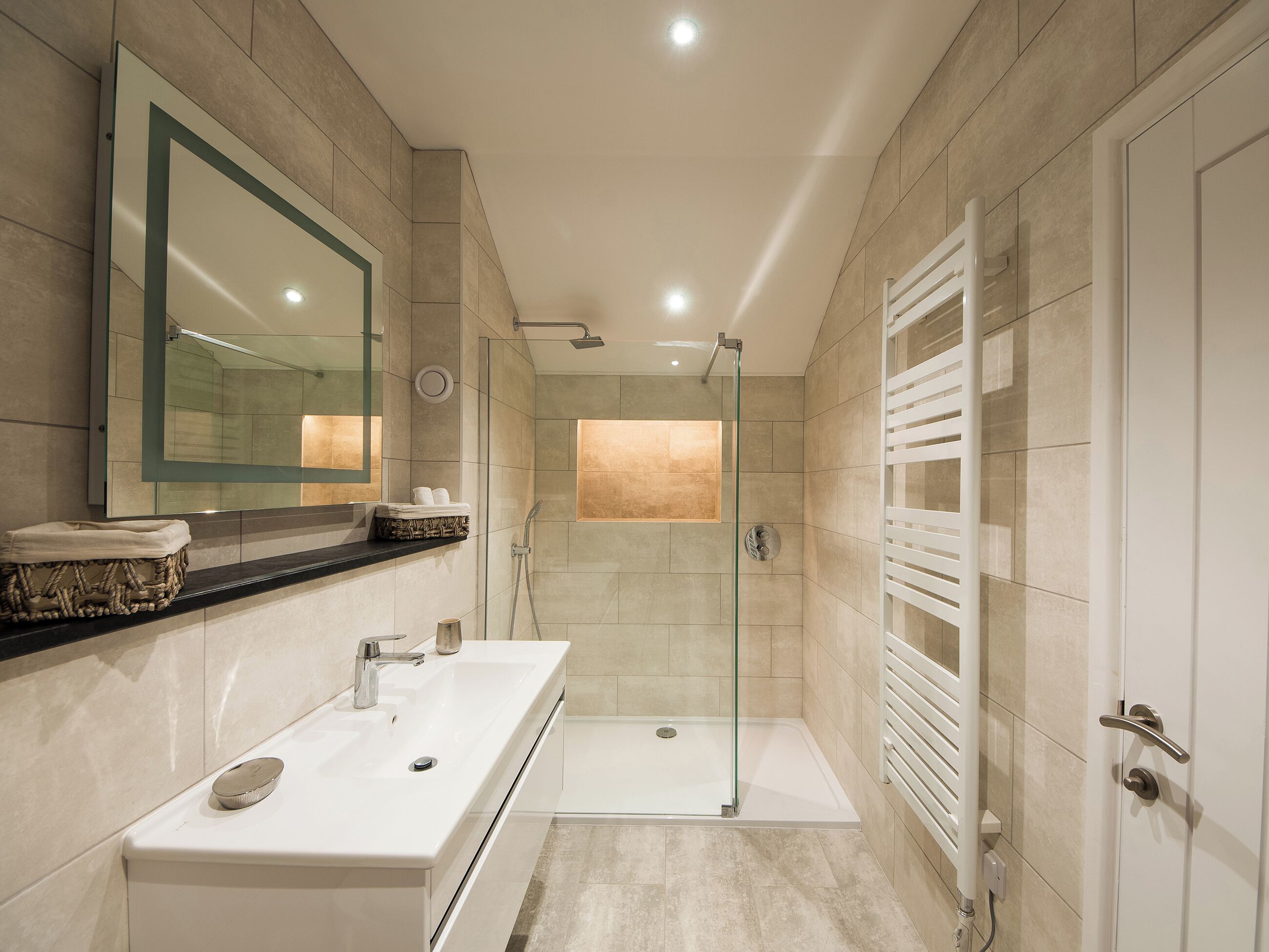 A modern bathroom with a glass-enclosed shower, a double sink vanity, and a large mirror.