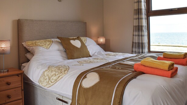 A bedroom with a bed, bedside lamps, a window with a view, and a wall decoration.