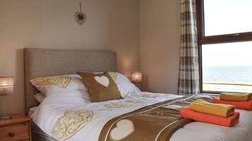 A bedroom with a bed, bedside lamps, a window with a view, and a wall decoration.