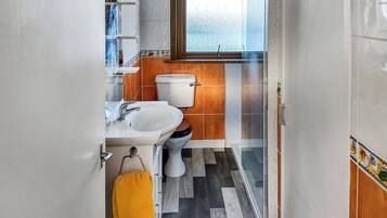 A bathroom with a toilet, sink, and a window.