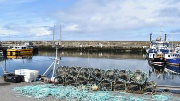A harbor with boats docked, fishing nets, and a calm sea.
