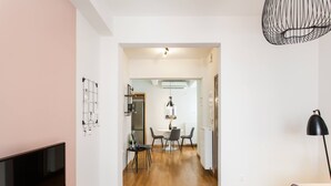 A modern living room with a flat-screen TV, a dining area with a table and chairs, and a black lamp. - Delightful 1BD Apartment in Plaka (Athens)