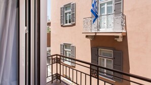 A building with a balcony featuring a flag, multiple windows with shutters, and a metal railing. - Delightful 1BD Apartment in Plaka (Athens)