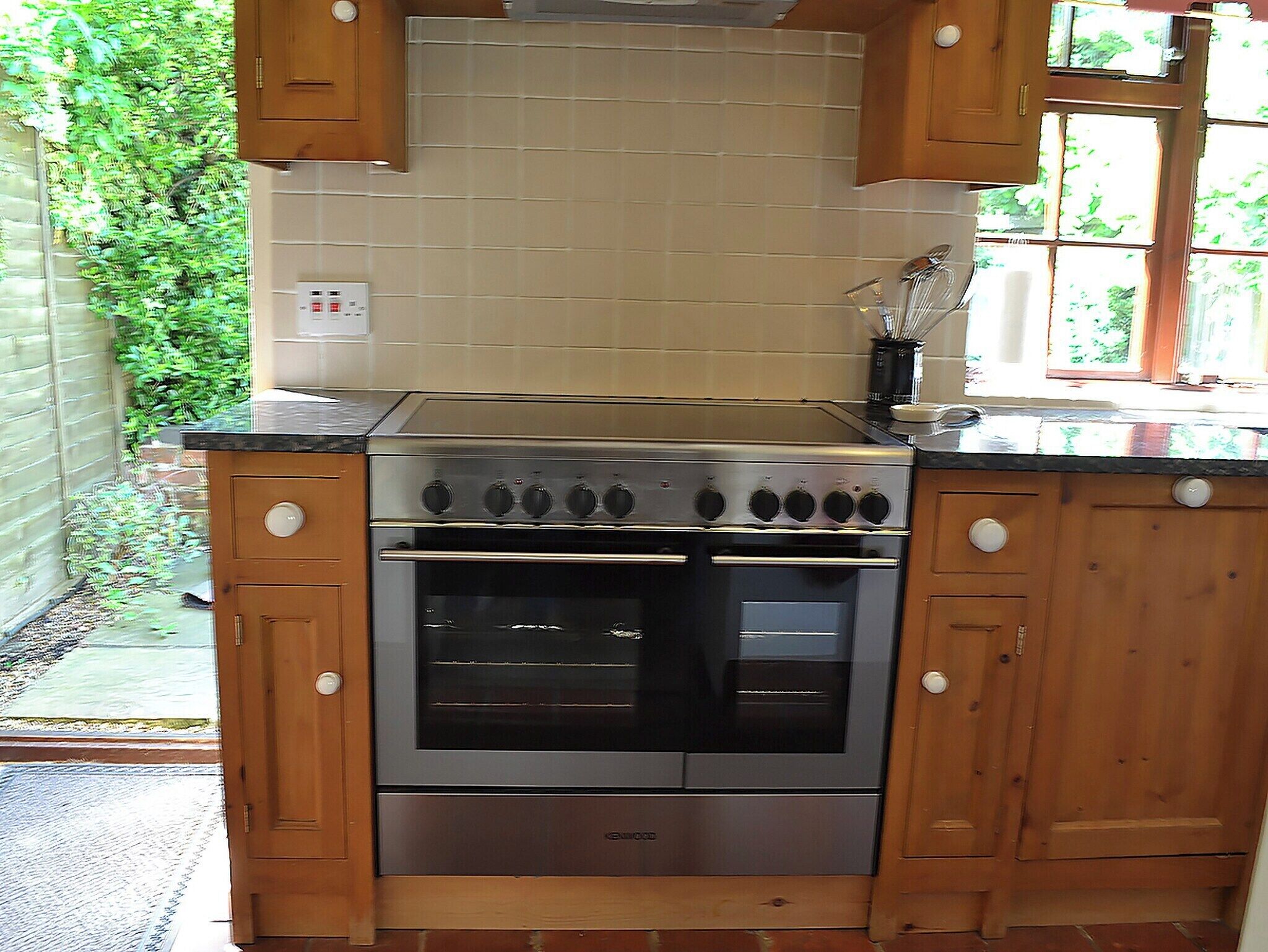 Cocina con gabinetes de madera, estufa de acero inoxidable y salpicadero de azulejos.