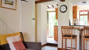 A cozy living area with a sofa, a dining table with chairs, and a kitchen visible through an open door. - 1 bedroom accommodation in Slingsby, near Malton (Slingsby, near Malton)