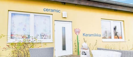 Un bâtiment jaune dont la façade porte les mots « céramique » et « Keramiikka », avec une porte et des fenêtres ornées d’œuvres d’art.