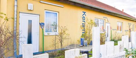 Un bâtiment jaune avec le mot « Keramik » écrit sur le côté, une porte et une fenêtre ornée d’un tableau.