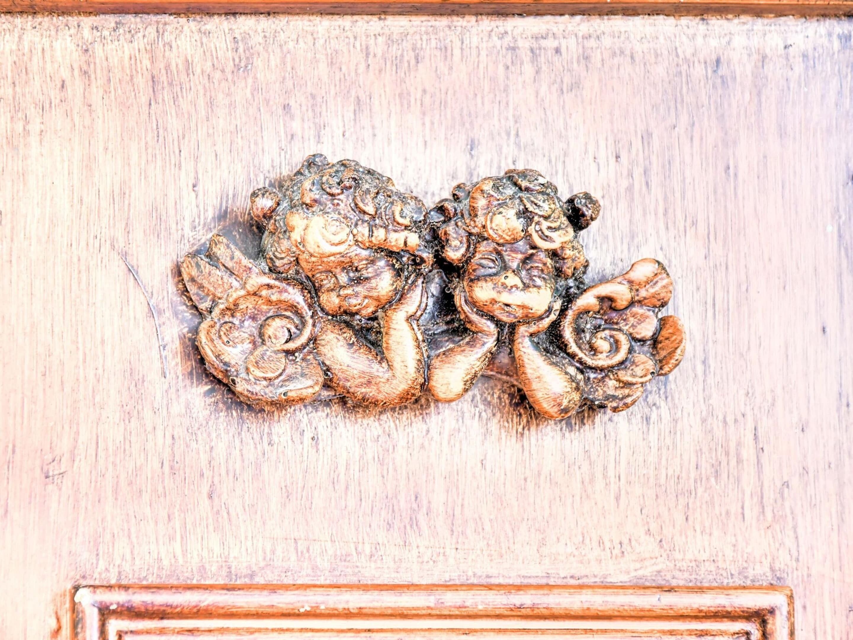 A carved wooden door with a detailed, ornate design featuring intertwined figures.