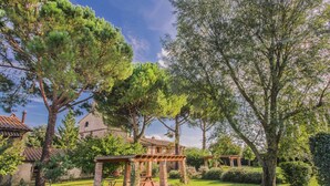 A garden with a pergola, a stone building, and a large tree. - Apartment With Swimming Pool in Marsciano (Marsciano)