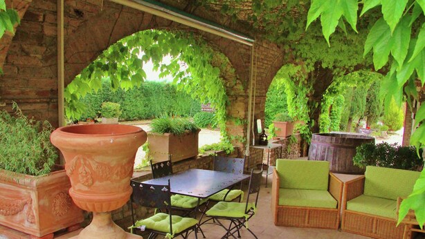 An outdoor patio with brick walls, green plants, and seating areas. - Apartment With Swimming Pool in Marsciano (Marsciano)
