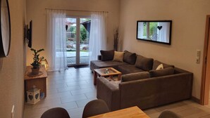 Uma sala de estar moderna com um sofá marrom, uma mesa de centro de madeira e uma televisão fixada na parede.