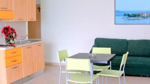 A modern kitchen with a sink, cabinets, and a dining area with a table and chairs. - Apartment in Residence on Lake Maggiore near Beach (Verbania)