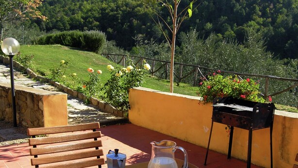 Une terrasse avec un banc en bois, un plateau sur lequel se trouvent une cafetière, un pot de confiture et une tasse.