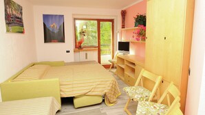 A bedroom with a bed, a desk, a chair, a wardrobe, and a window with a view of greenery. - Matterhorn View Apartment in Breuil-Cervinia near Ski Area (Valtournenche)