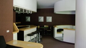 A modern bar area with high stools, a counter, and a seating area with tables and chairs. - Matterhorn View Apartment in Breuil-Cervinia near Ski Area (Valtournenche)