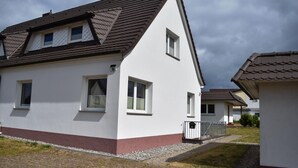 Una casa moderna a due piani con tetto spiovente, numerose finestre e un piccolo portico.