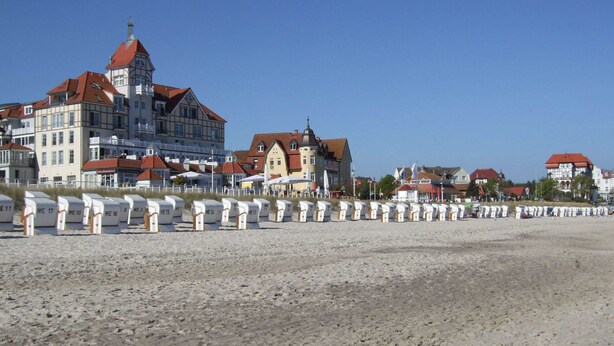 Un hotel sul lungomare con diversi edifici, una spiaggia sabbiosa e file di cabine.