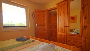 Una camera da letto con due letti, armadi in legno, una finestra e uno specchio.