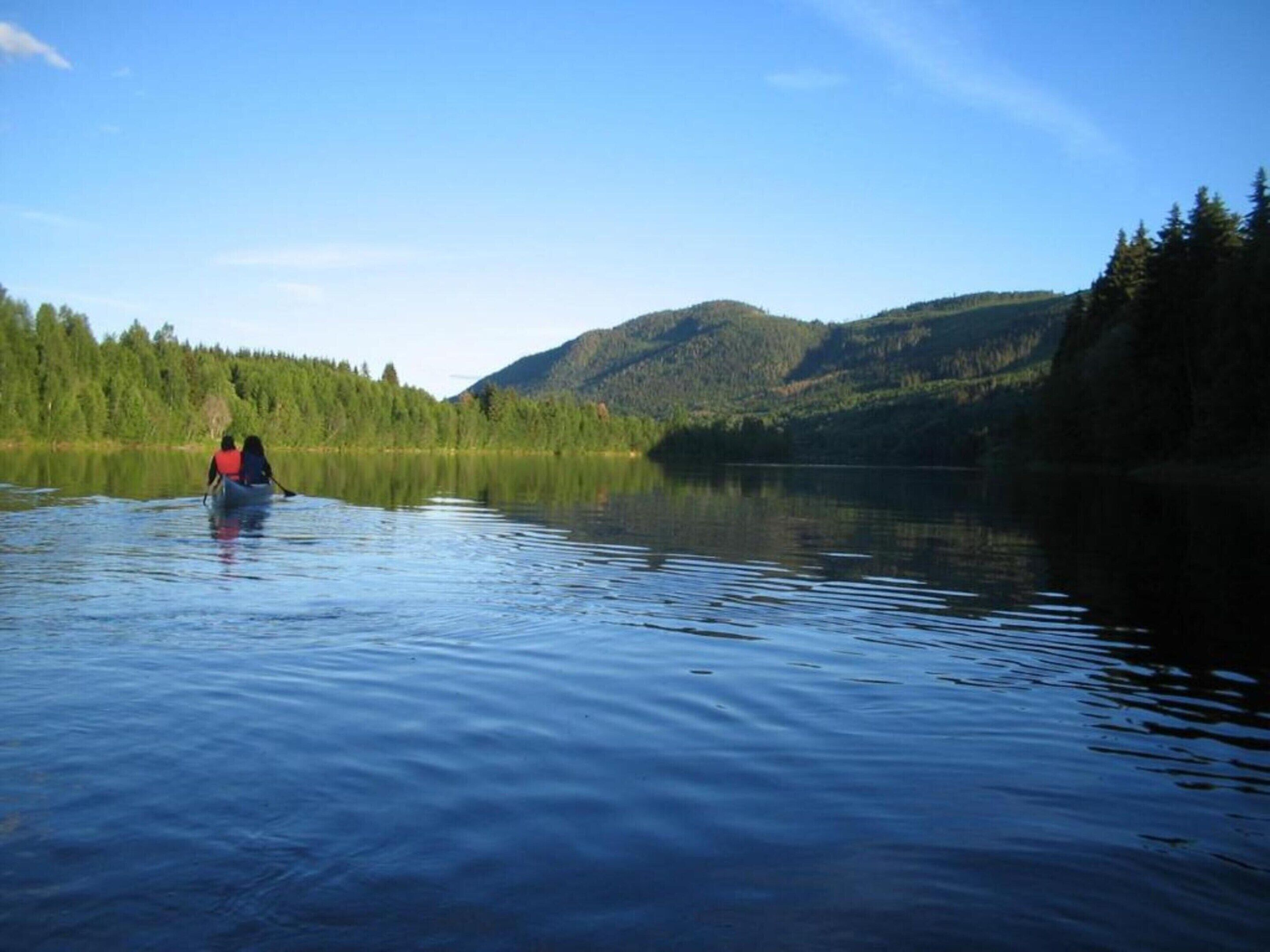 A calm lake with a canoe and two people paddling.