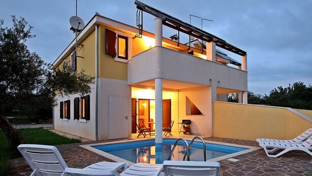 A two-story house with a swimming pool, outdoor seating, and a satellite dish.