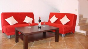 A room with two red sofas, a wooden coffee table, and a bottle of wine.
