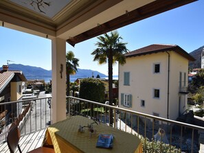 A balcony with a view of a lake and mountains, a table with a book, and a chair. - Spacious Retreat in Cannero (Cannero Riviera)