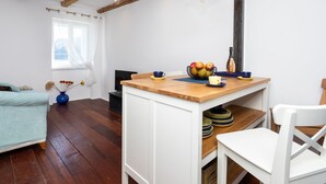 A cozy room with a wooden dining table, a white chair, and a bed with a blue cover. - Adorable Holiday Home Located Near the Beach (Baska)