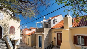 A narrow cobblestone street lined with traditional buildings, each with a distinct architectural style and a red-tiled roof. - Adorable Holiday Home Located Near the Beach (Baska)