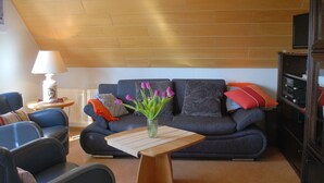Un salon chaleureux avec un canapé gris foncé, une table basse en bois et une lampe sur une table d’appoint.